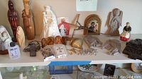 Overview of religious decor lot showing assorted figurines, crosses, plaques, decorative cards, and rosary beads arranged on a shelf.
