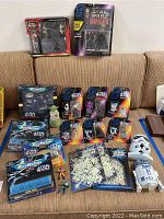 Full view of all Star Wars collectibles, toys and masks arranged on sofa, including Micro Machines sets, figures, masks, and decorations.