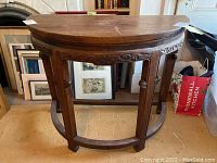 Front view of half-circle wooden table showing carved trim and legs