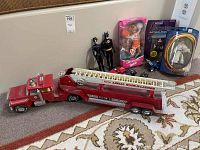 Photo showing red Nylint Aerial Hook-N-Ladder fire truck, two black Batman and Batwoman figures, boxed University Barbie doll, Shakespeare and Lord of the Rings figurines, and miniature cars.