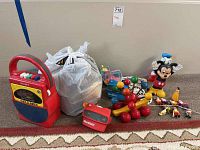 Overall lot including My First Sony cassette player/radio, plastic bags with parts, pull-behind toys, and Disney figurines Mickey Mouse and Donald Duck.