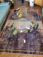 View of the full area rug under a glass coffee table showing the overall color, pattern, and condition.