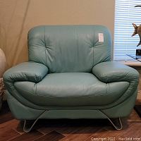 Front view of teal leather chair showing tufted back and metal sled legs