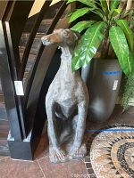 Front view of the sitting dog statue with textured surface and elongated legs.