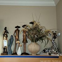 Full lot view showing figurines, vases, and giraffe statue on a shelf.