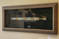Full frontal view of rectangular shadowbox containing decorative sword art.