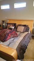 Full view of king size bed with bedding, headboard against wall, decorative pillows and comforter visible