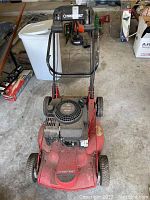 Front view of red Troybilt lawnmower with Briggs & Stratton Quantum 5 HP engine, showing handlebar and engine detail.