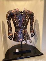 Front view of Patinated metal jacket torso sculpture on black rectangular base