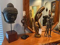 Overview of all four sculptures on a wooden dresser in front of a mirror