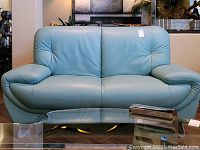 Front view of teal leather sofa showing seating area and metal legs.