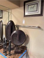 Wide shot of two large abstract face sculptures and two slender carved wood human figures displayed on a granite surface, zebra wall art visible on the wall above.