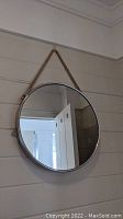 Round metal-framed mirror with rope hanger hanging on wall