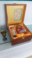 Wooden box containing Asian-style metal tea canister and vacuum tool on orange satin lining with lattice-design lid