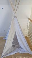 Front view of child's teepee showing wooden frame and linen fabric body with open entrance.