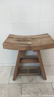 Side view of rustic teak wooden stool with natural wood grain and scratches on seat