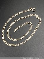 Full view of Figaro link chain laid on black background