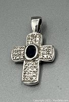 Front view of the 14Kt white gold cross pendant showing central sapphire and surface diamonds.