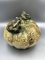 Front angled view of the porcelain pumpkin with two frogs on top showing glossy finish and detailed coloration