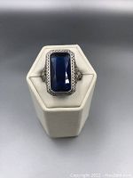 Top view of rectangular blue gemstone set in intricate sterling silver setting showing Victorian style design details.