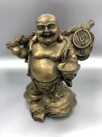 Front view of the Laughing Buddha statue showing the smiling face, bowl in hand, and walking stick with coins and sack over left shoulder.