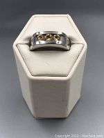 Front view of sterling silver ring with three citrine stones on white display stand.