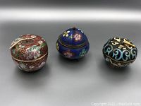 Three vintage cloisonné miniature lidded boxes shown together: apple shape, blue censer shape, and black gourd shape.
