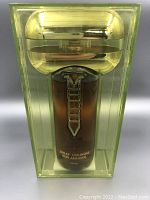 Front view of brown spray cologne bottle with silver Macho label inside yellow plastic case