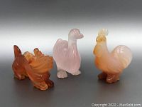 Front view of duck, rooster, and dragon semi-precious stone carvings showing their relative sizes and colors.