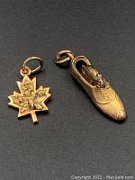 Close-up of front side of gold maple leaf charm and gold mouse in shoe charm showing details.