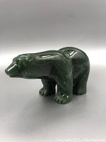 Side view of dark green jade bear carving showing polished surface and stylized form