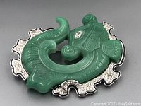Front view of green dragon brooch with silver-tone and rhinestone accents