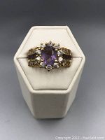 Front view of the vintage gold-tone and sterling silver ring showcasing the large oval amethyst center stone surrounded by smaller clear stones.