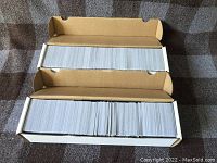 Top down view of two white cardboard boxes filled with Magic The Gathering cards placed side-by-side.