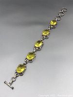 Full view of the vintage citrine bracelet laid flat to show the five large oval gemstones and silver-toned metal links.