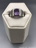 Front view of the sterling silver ring showing the deep purple amethyst center stone and side clear stones.