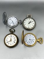 Four pocket watches arranged in single photo, showing front faces and open covers for Bulova and Roman numeral watches