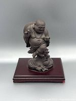 Front view of purple clay Happy Buddha figurine on wooden base