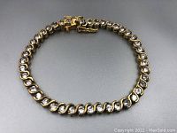 Full view of the gold washed sterling silver tennis bracelet showing circular links with clear stones and the clasp closed.