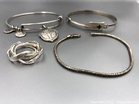 Lot overview showing three bracelets and one puzzle ring.