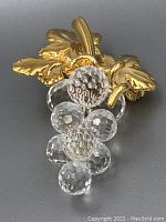 Front view of the grape bunch pin showing the clear faceted crystals and gold-tone leaves and stem.