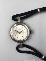 Front view of watch face showing white dial, silver-tone markers, and Tudor branding.