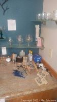 Wide view of barware glasses on shelves and bar tools with stir sticks and straws on countertop.