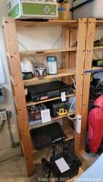Wooden shelving unit with items including Coleman camping stove, lanterns, and other accessories.