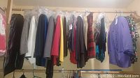 Clothes hanging on rack including blazers and shirts of various colors and patterns