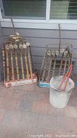 Two vintage croquet sets in original branded racks, showing wooden mallets and balls, placed outdoors on tile flooring against a gray wall.