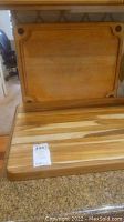 Large wood cutting board with some wear and decorative corner inlays, with smaller cutting board in front.