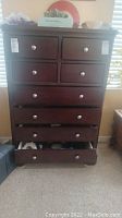 Front view of full dresser showing eight drawers with metal knob handles in dark wood finish. Slightly open drawers at bottom.