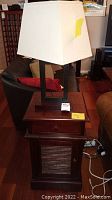End table with drawer and door below, hole in back for cords, dark mahogany finish, with table lamp on top