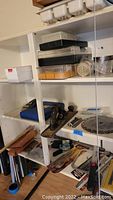 View of shelves containing plastic bins, a metal hand plane, and assorted tools.